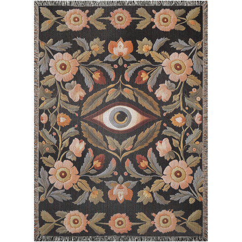 A luxury woven jacquard blanket in three sizes featuring an all-over wild herb botanical pattern of stylized blossoms and foliage in muted gold, olive, lavender, and pewter on a deep black cotton ground; finely twisted multicolor fringe edges complete the artful tapestry weave, ideal as a cozy sofa throw or dramatic wall hanging.